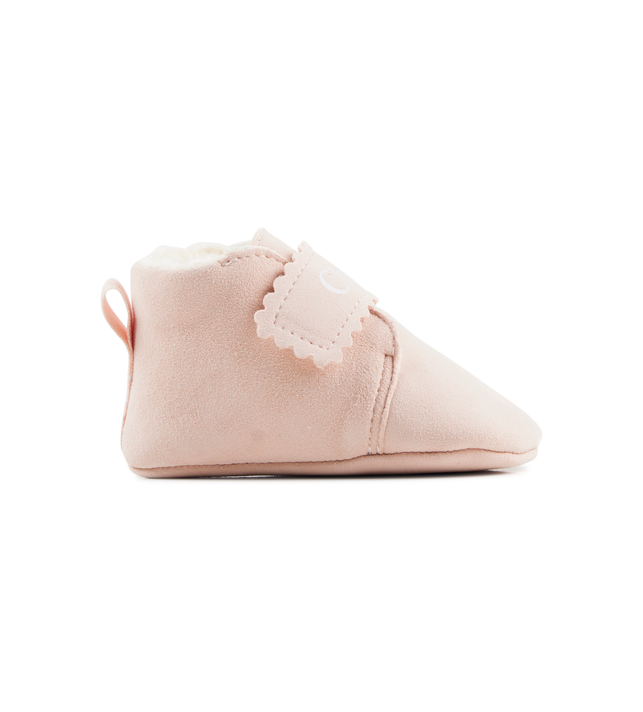 Pink baby bootie with lace trim on a white background