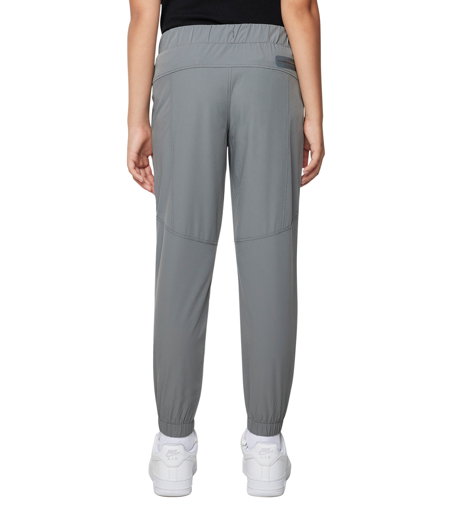 Person wearing a black sleeveless top and gray pants on a white background
