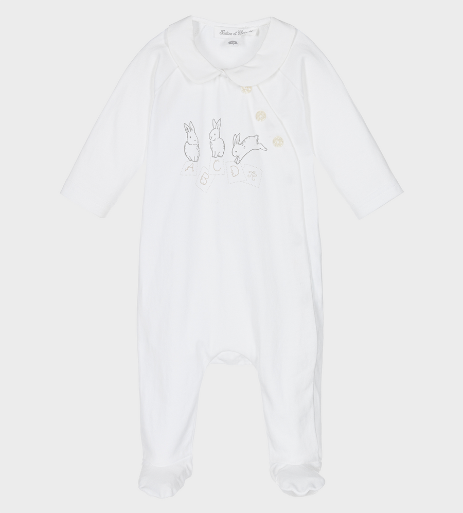 White bodysuit with graphic print to the front, featuring a Peter Pan collar and off-centre front button fastening. It has long sleeves and covers the foot.