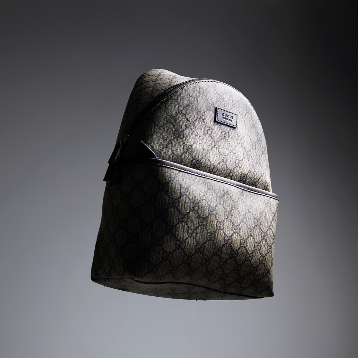 Gray quilted backpack on a dark gradient background