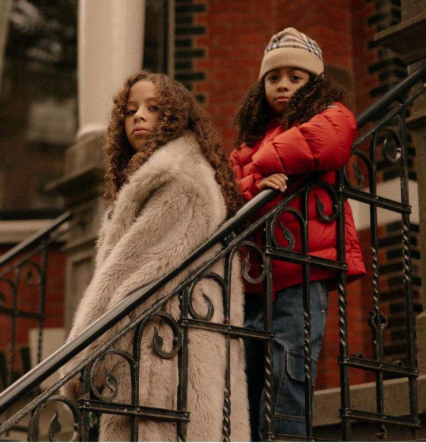 Two children standing on a staircase with a brick building in the background