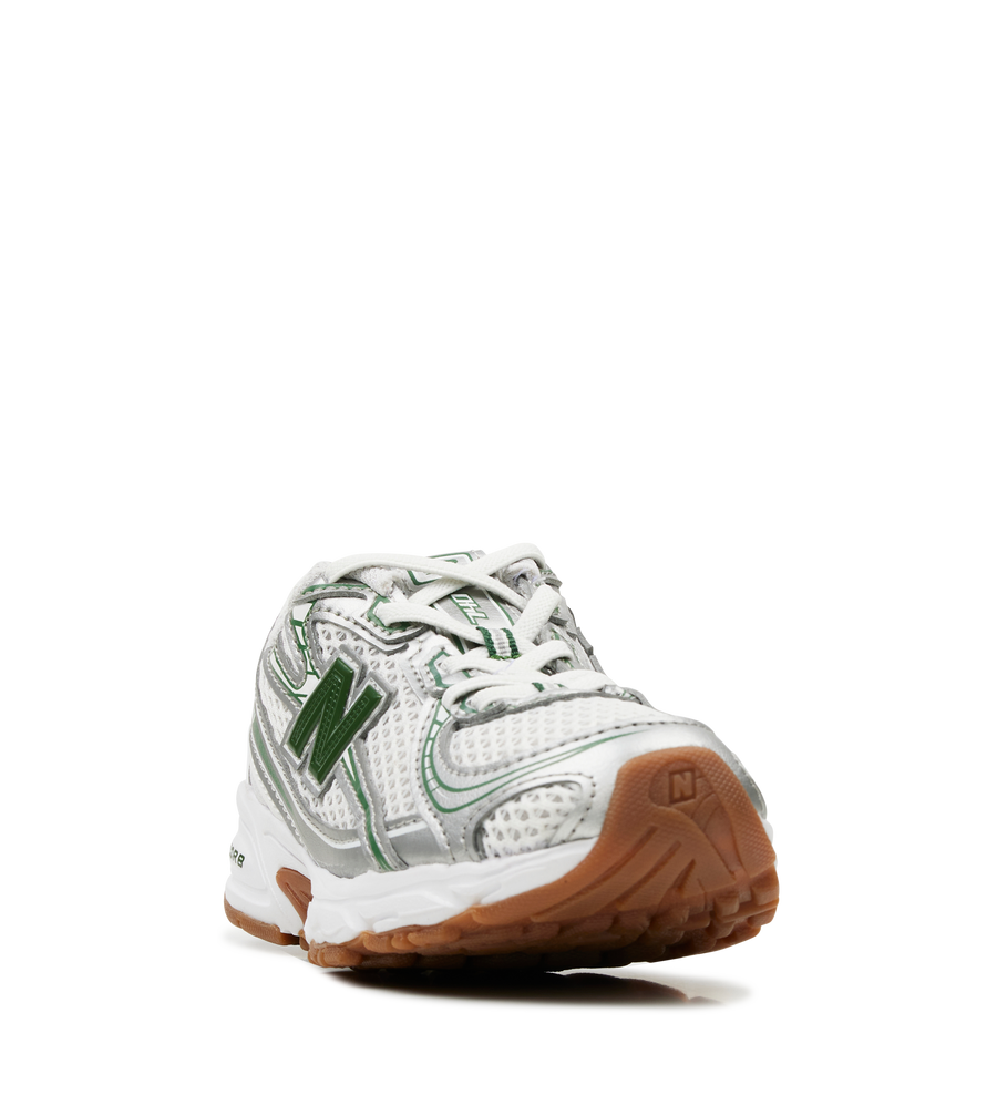 White sneaker with green accents and brown sole on a white background